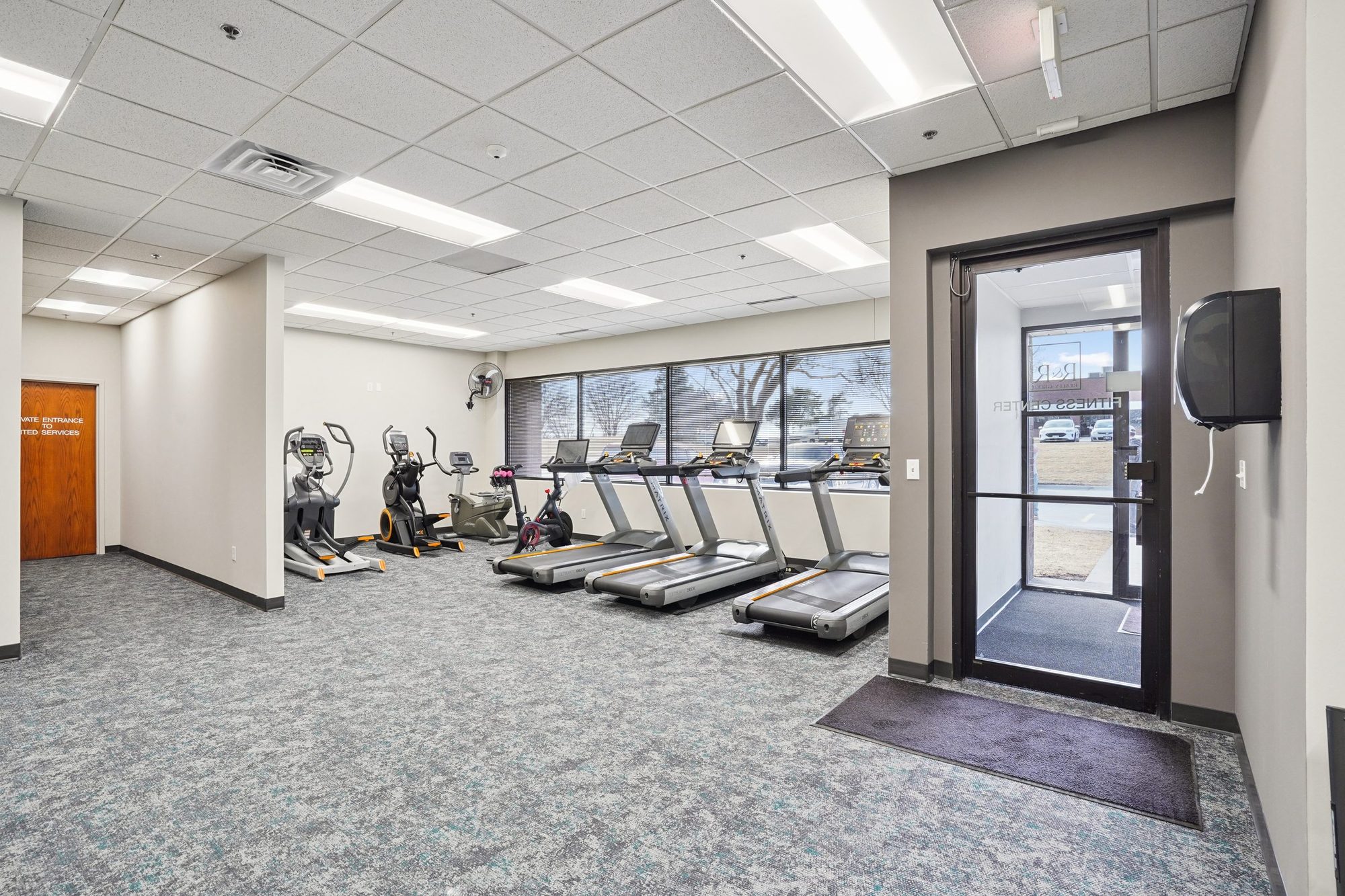 Fitness Center — main entry with cardio equipment and window wall